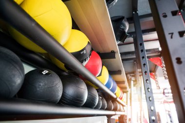 Spor salonundaki dayanıklılık eğitimi için raflarda duran kauçuk tıp topları..