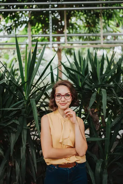 stock image Businesswoman selling flowers and seedlings, standing in greenhouse, looking at camera, smiling. Small greenhouse business.