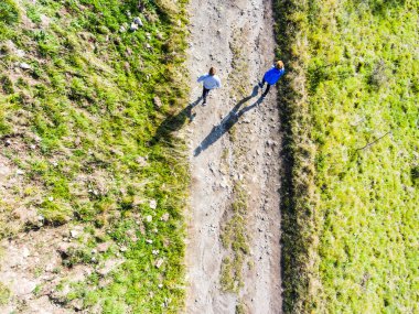 Toprak yolda koşan iki koşucunun hava görüntüsü. İki erkek arkadaş için sabah antrenmanı..