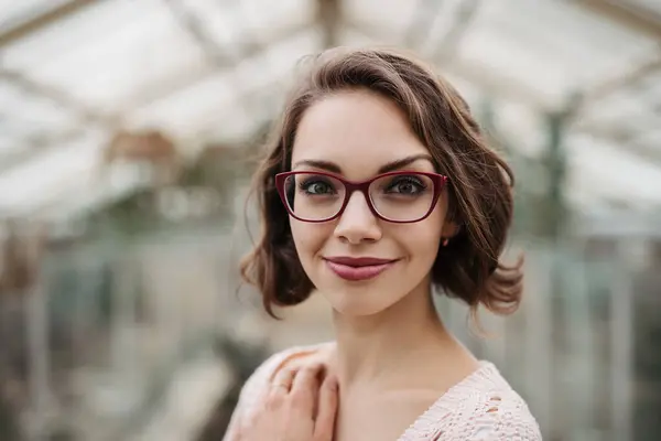 stock image Businesswoman selling flowers and seedlings, standing in greenhouse, looking at camera, smiling. Small greenhouse business.