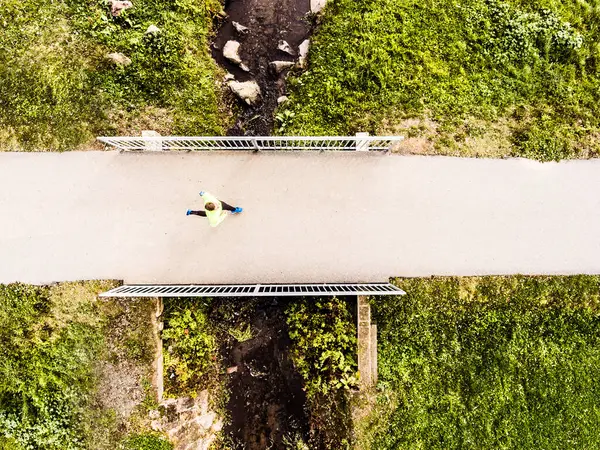 stock image Aerial view of a runner running across the bridge in park on a jogging path. Morning running training.