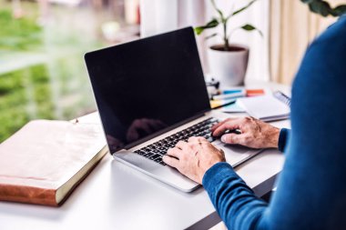 Yakışıklı adam için ev ofisi. Evden bilgisayarla çalışan bir adam. Uzak çalışma.