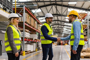 Mühendisler modern sanayi fabrikasında proje yöneticisiyle el sıkışıyorlar, yeni üretim projesi, yatırım hakkında konuşuyorlar. Üretim tesisinde takım yönetimi.