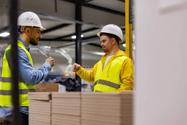 stock image Young man with Down syndrome working in modern factory, fist bump with colleague. Concept of workers with disabilities, support in the workplace.