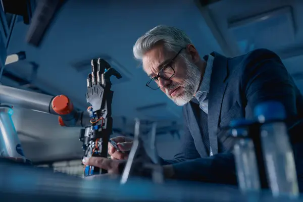 stock image Robotics engineer adjusting, calibring robotic prosthetic artificial hand. Concept of modern technology in medicine. Robotic prosthetics, biomechatronics and neuroscience.