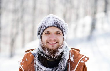 Karlı doğadaki genç bir adamın portresi, kar kıyafetlere ve sakala yapıştı. Mevsimin ilk karı