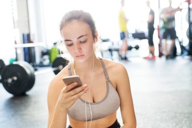 Genç fitness kızı spor salonunda sıkı çalıştıktan sonra smatphone 'da performansını kontrol ediyor..