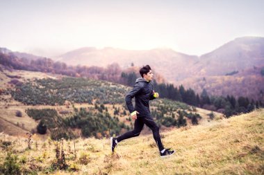 Erkek koşucu, toprak yolda doğada koşuyor. Genç adam için sabah koşusu eğitimi.