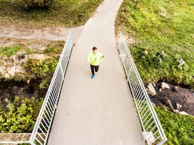 Koşu parktaki köprüde koşan bir koşucunun hava görüntüsü. Sabah koşusu eğitimi.