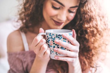 Kıvırcık saçlı güzel genç bayan için sabah çayı. Dişi çay aşığı sade kahve yerine yeşil çay içiyor.