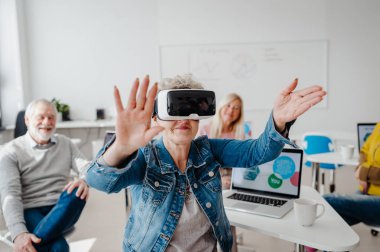 Bilgisayar ve teknoloji eğitimi dersinde VR gözlüklü bir grup son sınıf öğrencisi. VR kulaklığı kullanarak sanal gerçekliği öğrenen yaşlı insanlar