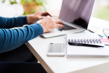 Ajandada notlar yazan, evden masa başında çalışan bir adam. Telekomünikasyon ve ev ofisi