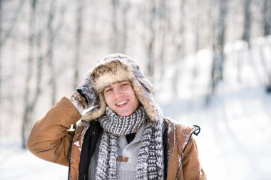 Karlı doğadaki genç bir adamın portresi, kıyafetlere sıkışmış kar. Mevsimin ilk karı