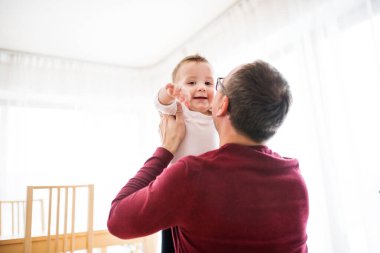 Baba küçük oğlunu havada tutuyor, onunla oynuyor.