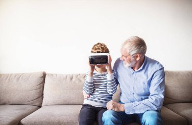 Oğlan ve büyükbaba VR kulaklığı deniyor. Dedem torunu ile vakit geçirir. Ebeveynleri işteyken ona bakar.
