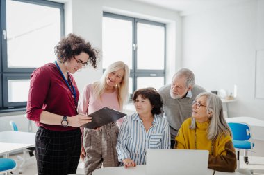 Öğretmen son sınıf öğrencilerine kendi işlerini nasıl kuracaklarını anlatıyor. Bilgisayar ve teknoloji eğitimine katılan yaşlılar. Yaşlılar için girişimcilik programı