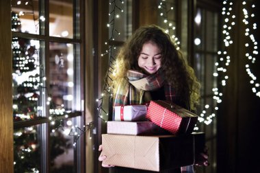 Genç bir kadın Noel hediyesi almak için alışveriş yapıyor, elinde hediyelerle mağazadan çıkıyor..