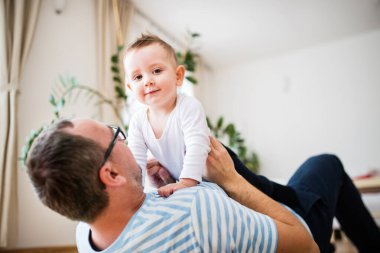 Babasının portresi küçük oğluyla oynuyordu, yerde yatıyordu ve kucağında küçük bir çocuk vardı.