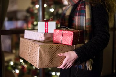 Genç bir kadın Noel hediyesi almak için alışveriş yapıyor, elinde hediyelerle mağazadan çıkıyor..