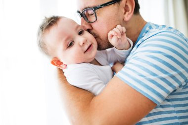 Küçük oğluyla babasının portresi. Babam oğlanı yanağından öpüyor ve sarılıyor.