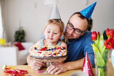 Küçük kız için doğum günü pastası ile doğum günü partisi. Bekar baba ve kızı birlikte kutluyorlar.