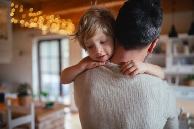 Babası küçük oğlunu kollarında tutuyor, ona sarılıyor. Babalık ve Babalar Günü konsepti.