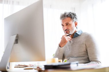 Yakışıklı adam için ev ofisi. Adam notlar yazıyor, evden masa başında çalışıyor. Uzak çalışma.