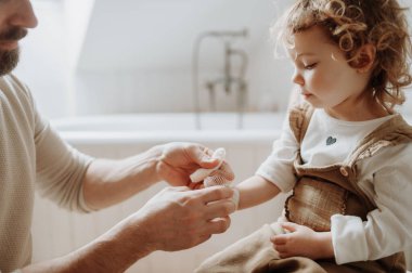 Babam banyoda yaralı bileklerini bandajlıyor. Bandaj kullanırken konsantre oluyor.