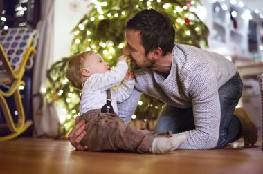 Noel evinde küçük bir oğlan. Yakışıklı çocuk, babamı Noel kurabiyeleriyle besliyor oturma odasında, eğleniyor..