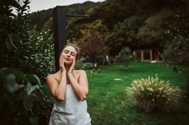 Ev saunasından sonra bahçede dinlenen güzel bir kadın. Kadın vücudu ve zihni ile ilgileniyor, sağlık rutini.