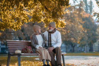 Güz parkında bankta oturan güzel son sınıf çifti. Yaşlı karı koca birbirlerine sevgiyle bakıyorlar..