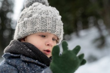Küçük bir çocuğun portresi. Ailesiyle dağlarda kış tatilinin tadını çıkarıyor. Karda oynuyor..