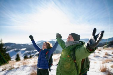 Kış ortasında kollarını açıp gülümseyen aktif yaşlıların portresi..