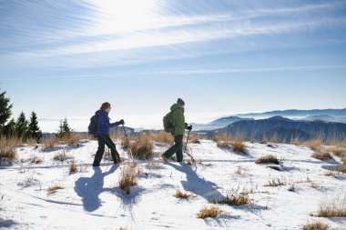 Karlı kış doğasında yürüyen aktif yaşlılar. Karlı dağlarda yaşlı bir çift için romantik kış yürüyüşü