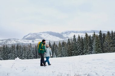 Dad and girl in the middle of snowy nature. Hiking in winter mountains. clipart