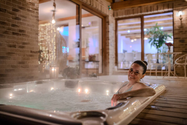 A blissful woman is relaxing in a hot tub. Single woman celebrating Valentines Day alone.
