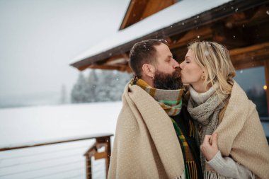 Olgun bir çift sevgililer gününü dağ evinde geçiriyor. Karlar yağarken karı koca terasta öpüşürler..
