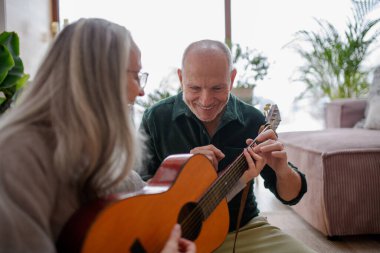 Evde daha yaşlı bir çift var. Koca karısına gitar çalmayı öğretiyor, eğleniyor ve gülüyor..