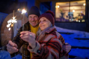 Mutlu son sınıf çifti yeni yılı maytaplarla kutluyor, kış akşamının tadını çıkarıyor..