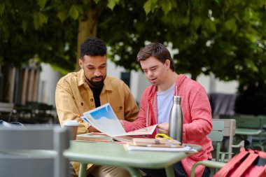 Down sendromlu genç bir adamda çoklu duyusal öğretim yöntemleri kullanan özel eğitimci. Özürlü bir adam, dışarıda kafede oturan akıl hocası bir arkadaşla vakit geçiriyor..