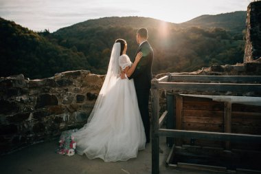Genç bir çift sarılıyor, bakış açısına göre duruyor ve etraflarındaki manzaraya bakıyor..