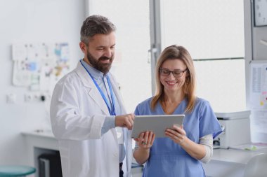 Doktor ve bayan hemşire tabletteki test sonuçlarına bakıyor. Doktorların ofisinde, klinikte sağlık çalışanları.