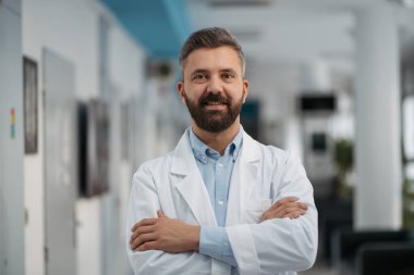 Hastane koridorunda gülümseyen ve kameraya bakan yakışıklı bir doktorun portresi..