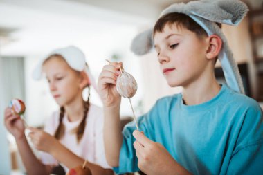 Girl and boy paiting eggs for easter. Siblings decorate egshells for easter egg decorating. clipart