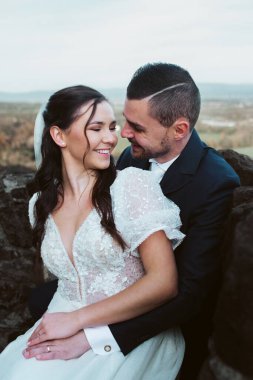 Gelin ve damat birbirlerine sevgiyle bakıyor, portre yapıyorlar. Güzel bir çift dışarıda oturuyor..