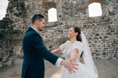 Gelin ve damat dans ediyor, birbirlerine bakıyorlar. Dışarıda yıkıntıların yanında duran güzel bir çift..