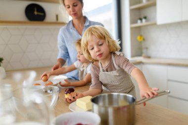 Nükleer aile birlikte krep yapıyor. Ebeveynler ve çocuklar mutfakta, krep hamuru hazırlıyorlar, hafta sonunu evde geçiriyorlar..