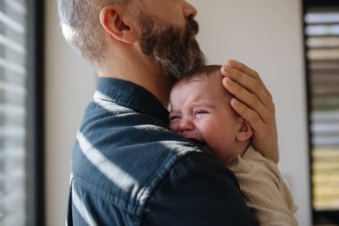 Baba ağlayan oğlunu teselli ediyor, onu kollarına alıyor..