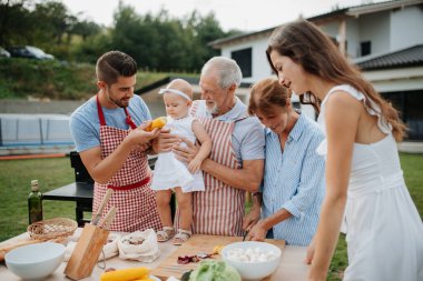 Üç nesildir aile bahar hafta sonu barbeküsü için yemek hazırlıyor. Bahçe partisi.