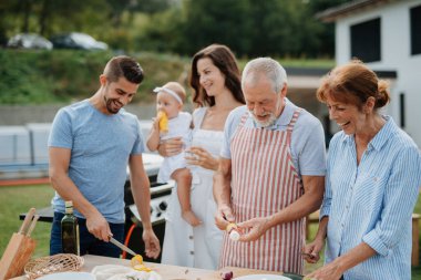 Üç nesildir aile bahar hafta sonu barbeküsü için yemek hazırlıyor. Bahçe partisi.